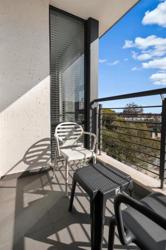 a balcony with two chairs and a table and a window at Easy Stay - The Vantage Rosebank in Johannesburg