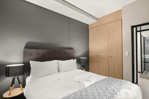 a bedroom with a white bed and a wooden cabinet at Easy Stay - The Vantage Rosebank in Johannesburg