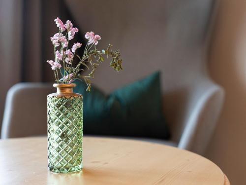 a vase with pink flowers sitting on a table at Hotel Weingut Innerleiterhof in Schenna