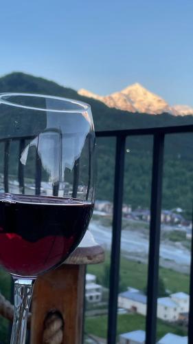 a glass of wine sitting on top of a balcony at Guest House Keti Margiani Mestia in Mestia