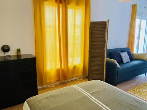 1 dormitorio con cortinas amarillas y sofá azul en L'Escale Catalane, 50m de la plage, 36m2, parking, en Canet-en-Roussillon