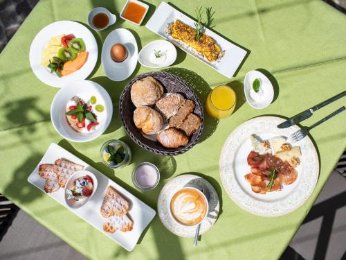 a green table with plates of food on it at Hotel Weingut Innerleiterhof in Schenna