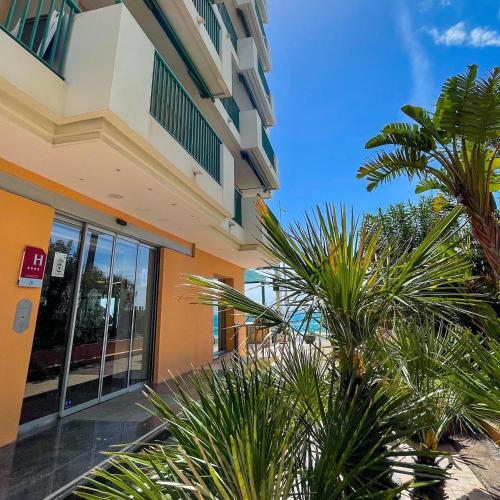 un bâtiment avec des palmiers devant dans l'établissement Princess Et Richmond, à Menton