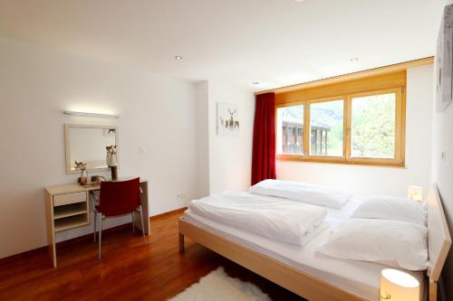 a bedroom with a bed and a desk and a window at Aramis in Saas-Fee