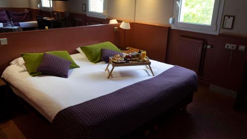 a bedroom with a large bed with a table on it at The Originals City, Hôtel Ascotel, Lille Est Grand Stade in Villeneuve d'Ascq