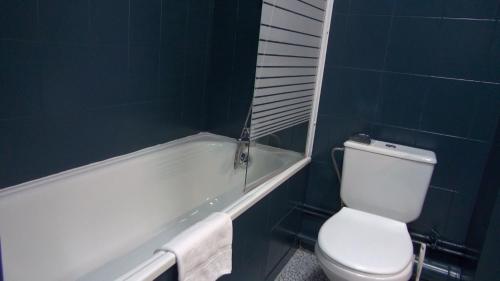 a bathroom with a toilet and a bath tub at The Originals City, Hôtel Ascotel, Lille Est Grand Stade in Villeneuve d'Ascq