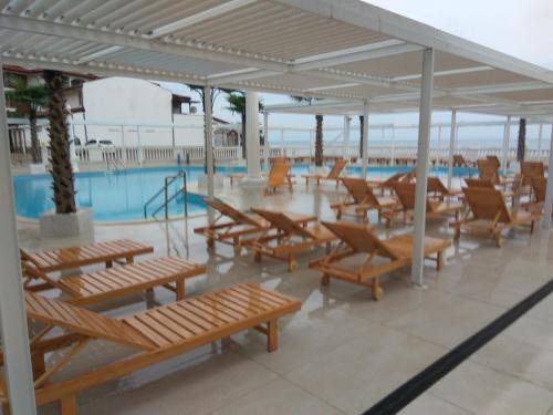 a pool with wooden benches next to a swimming pool at Апартаменты Талиана Бич курорта Елените in Elenite