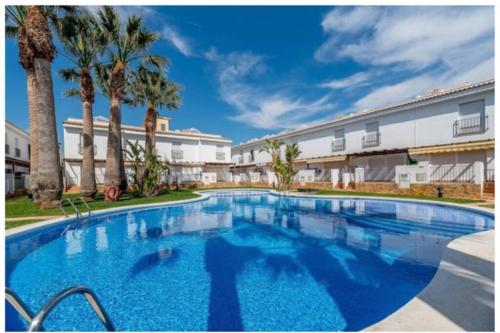 a large swimming pool with palm trees in front of a building at ENCANTADORA CASA CON PISCINA A 5 MIN PLAYA WIFI in Alcossebre
