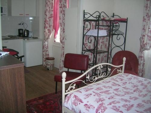 バニョール・ドゥ・ロルヌにあるStudette Villa Odetteのベッドルーム1室(ベッド1台、赤い椅子2脚付)