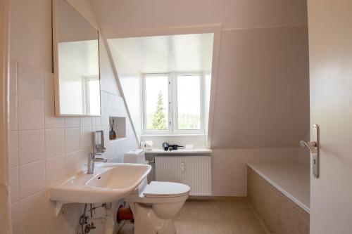 uma casa de banho com um lavatório, um WC e uma janela. em Lake Views em Grasten