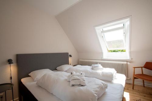 a bedroom with three beds with white sheets and a window at Lake Views in Gråsten