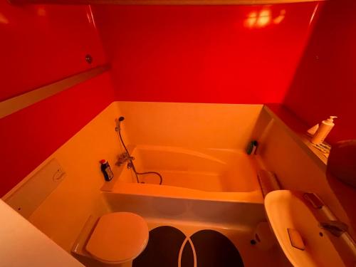 La salle de bains rouge est pourvue d'une baignoire et de toilettes. dans l'établissement Le choucas - Les Arcs, à Arc 2000