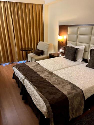 a hotel room with two beds and a chair at Europa Hotel in Kastoria