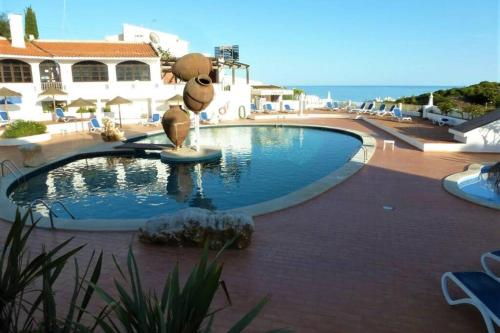 a large swimming pool with a statue in the middle at Apartamento Salema 33 in Salema