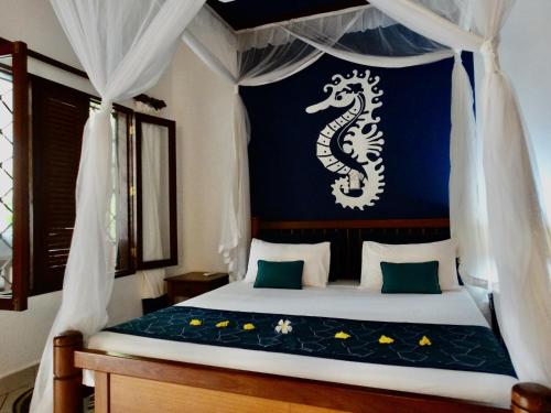 a bedroom with a bed with a dragon on the wall at Diani Cottages in Diani Beach