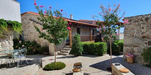 a stone house with a table and two trees at Casas de Campo da Barroca in Tabosa