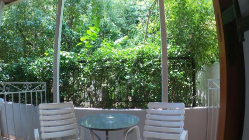 a glass table and two white chairs on a porch at Seamore Pension in Galaxidhion