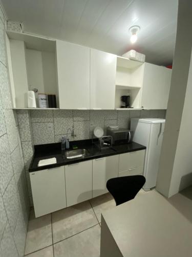 une cuisine avec des placards blancs et un comptoir noir dans l'établissement Moradas Pará Satélite 303, à Belém