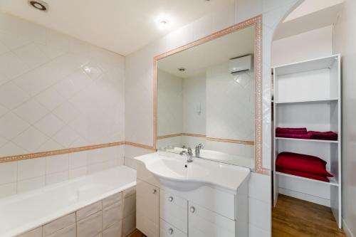 une salle de bain avec un lavabo, une baignoire et un miroir dans l'établissement Appartement de grand standing, joliment décoré, à Marseille