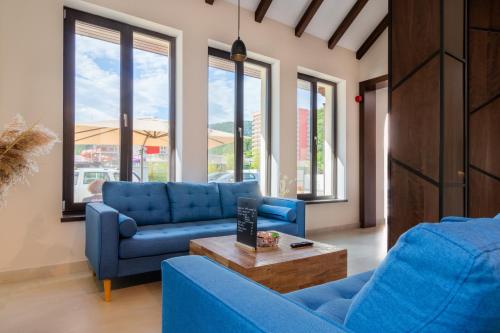 a living room with two blue couches and a table at RIVER Hotel & SPA in Călimăneşti