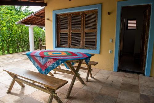 a table and a bench on the porch of a house at Chalé Aroeira Taiba in Taíba