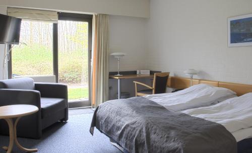 a bedroom with a bed and a chair and a desk at Hovborg Kro in Hovborg