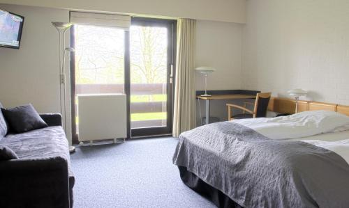 ein Schlafzimmer mit einem Bett, einem Sofa und einem Fenster in der Unterkunft Hovborg Kro in Hovborg