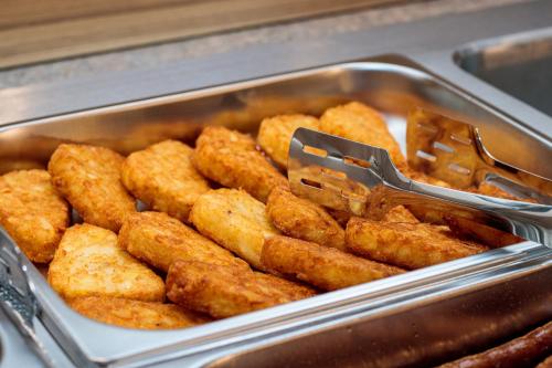 a metal pan filled with fried food with tongs at RIVER Hotel & SPA in Călimăneşti