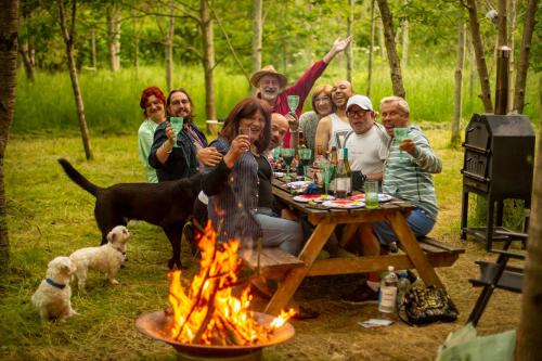 a group of people sitting around a picnic table near a fire at DGG Woodland Escape in South Barrow