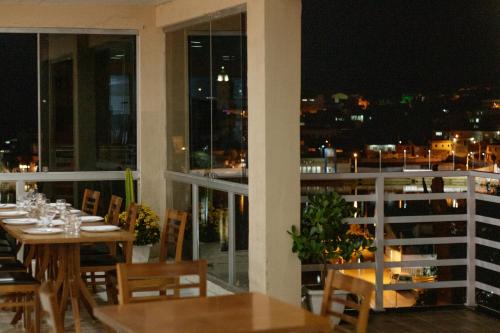 a restaurant with tables and chairs on a balcony at night at Pousada Alpes in Triunfo
