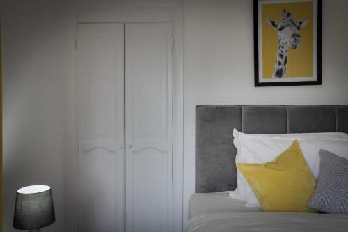 a bedroom with a bed with a giraffe picture on the wall at Spacious Three Bedroom House - Free Parking & Wifi in Chelmsford