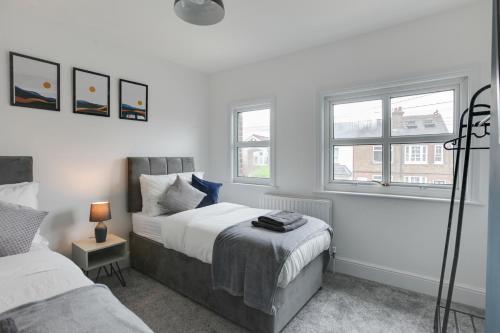 a bedroom with two beds and two windows at Spacious Three Bed Central Chelmsford House - Free Parking & Wifi in Chelmsford