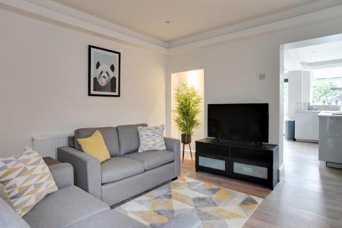 a living room with a couch and a flat screen tv at Spacious Three Bedroom House - Free Parking & Wifi in Chelmsford