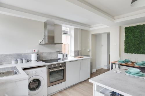 a white kitchen with a sink and a dishwasher at Spacious Three Bedroom House - Free Parking & Wifi in Chelmsford