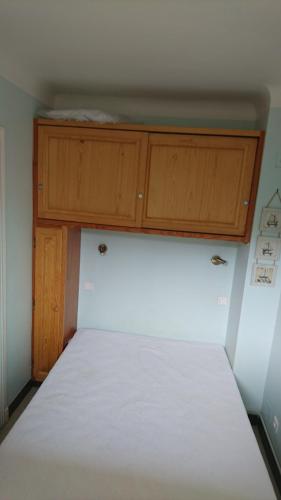 - un lit blanc dans un dortoir doté d'armoires en bois dans l'établissement APT FRONT DE MER DANS RESIDENCE LUXE SECURISEE, à Banyuls-sur-Mer