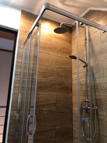 a shower in a bathroom with a wooden wall at Bier-Lak Apartman House 71 in Balatonlelle