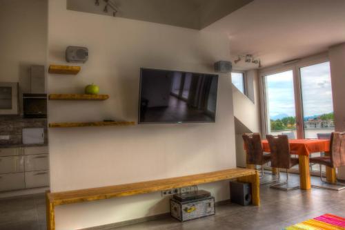 a living room with a table and a television on a wall at Alpenblick 2 in Lindau-Bodolz