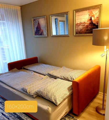 a small bed in a room with pictures on the wall at Orange Studio in Juodkrantė