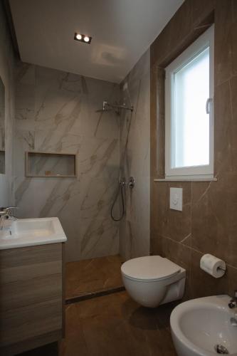 a bathroom with a toilet and a sink and a window at Premium Villas Resort in Shëngjin