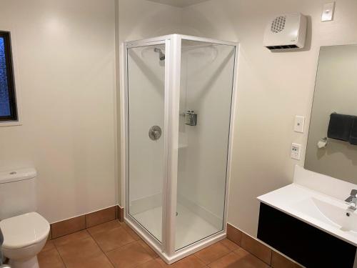 a shower in a bathroom with a toilet and a sink at ASURE Townsman Motor Lodge in Invercargill