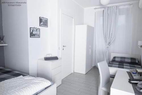 a small white room with a bed and a table at Affittacamere Villa Marcella in La Spezia