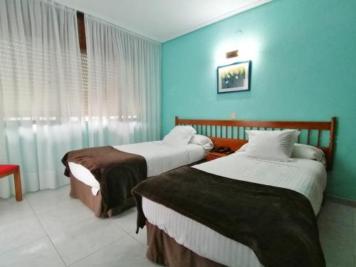 two beds in a room with blue walls at Hotel Las Rocas de Isla in Isla
