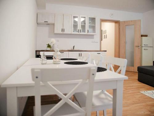 a white kitchen with a white table and chairs at Apartmány Říčky "Sněženka" in Říčky