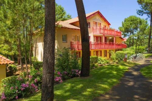 a large yellow house with a red balcony at L'orée des Pins TROPICO Appartement T2 en RDC avec terrasse refait à neuf in Lacanau