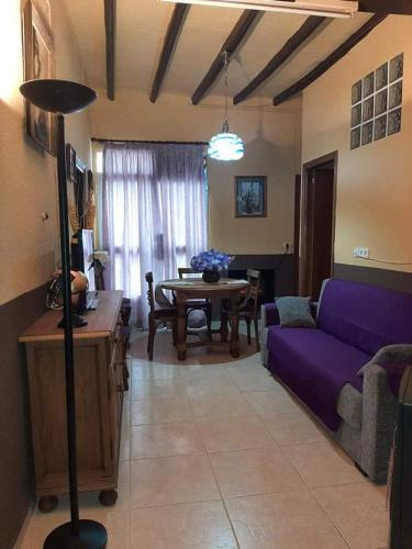 een woonkamer met een paarse bank en een tafel bij ALOJAMIENTO RURAL LOS MOLINOS in Gátova