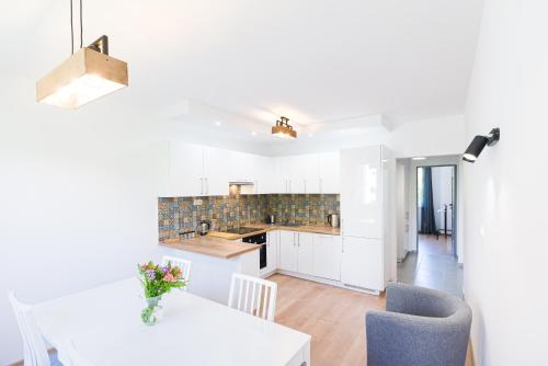 a kitchen with white cabinets and a table and chairs at Cisna Apartament in Cisna