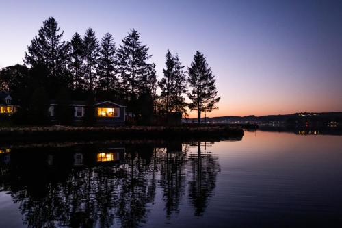 a house on the shore of a lake at sunset at Lighthouse Motel and Cottages in Bridgewater
