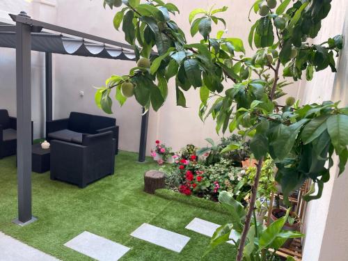 a patio with green grass and a chair and flowers at Camp Nou Nueva Casa in El Arrabal
