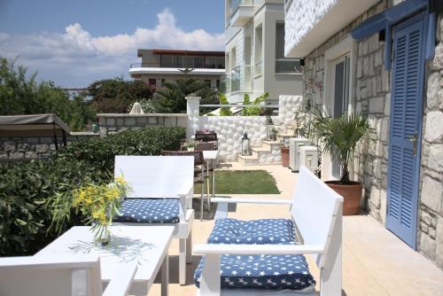 En un edificio hay un patio con mesas y sillas blancas. en Tepe Hotel, en Alacati