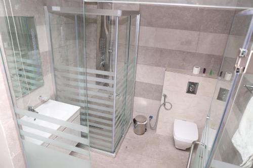 a bathroom with a shower and a sink and a toilet at AlQimah Hotel Apartments in Amman